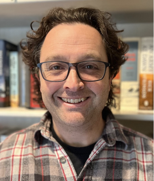 a man wearing glasses and smiling at the camera