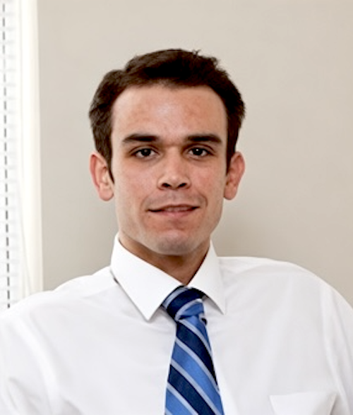 a man wearing a suit and tie smiling at the camera