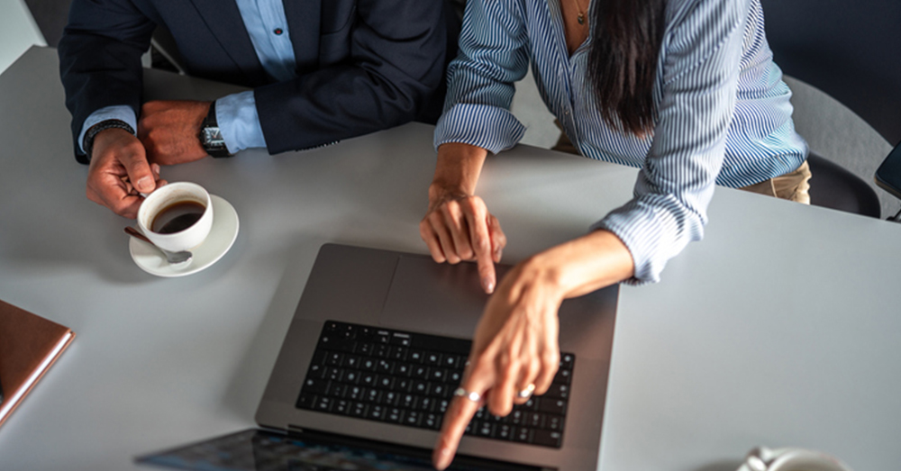 a group of people sitting at a table using a laptop